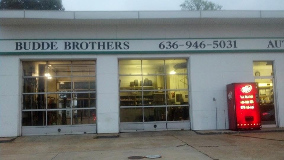 The two service bays at Budde Brothers lit up at dusk, tires and parts on the shelves inside